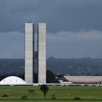 Vista do Congresso Nacional do Brasil, com suas cúpulas e torres diante de um céu claro.