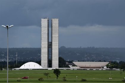 Vista do Congresso Nacional do Brasil, com suas cúpulas e torres diante de um céu claro.