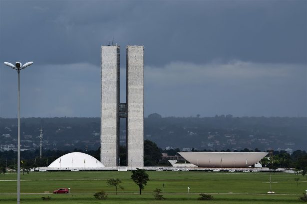 Vista do Congresso Nacional do Brasil, com suas cúpulas e torres diante de um céu claro.