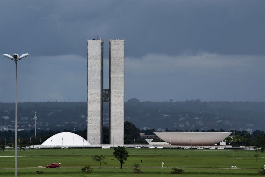 Vista do Congresso Nacional do Brasil, com suas cúpulas e torres diante de um céu claro.