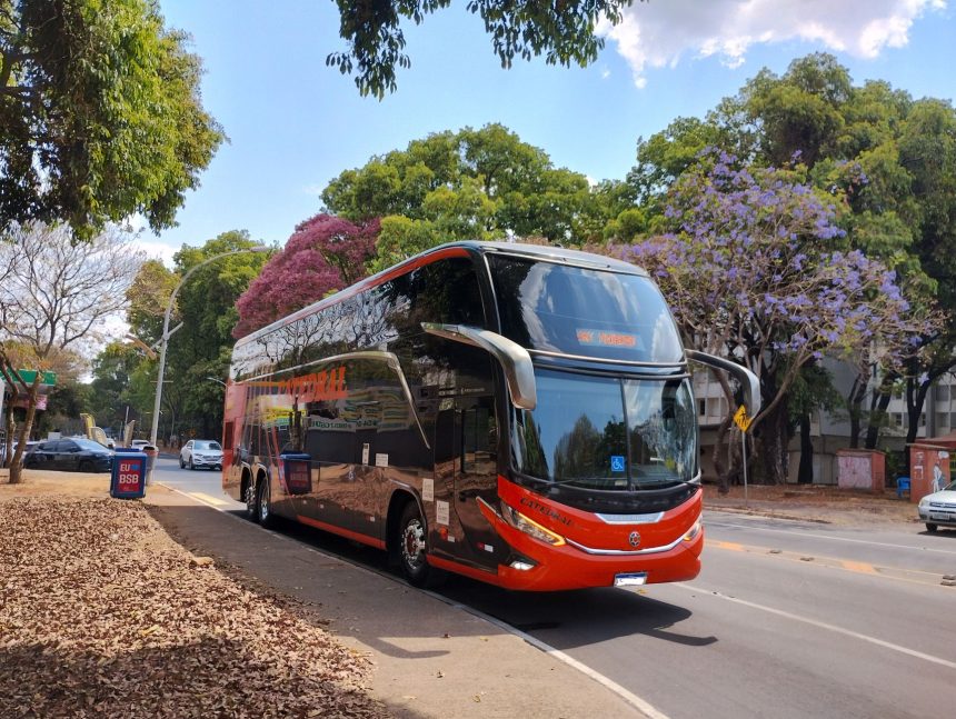 Ônibus urbano de dois andares circula por uma via arborizada de Brasília em um dia ensolarado.